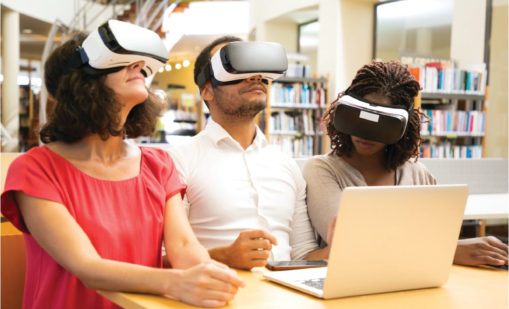 Three people using VR headsets with a laptop