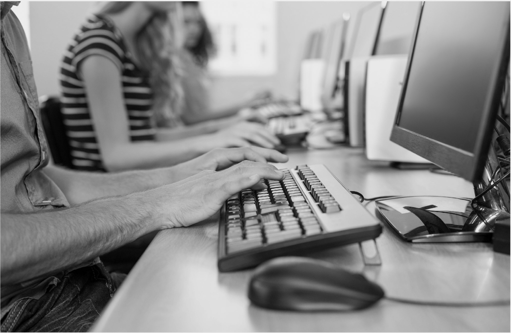 Hands typing on a computer keyboard in a lab setting