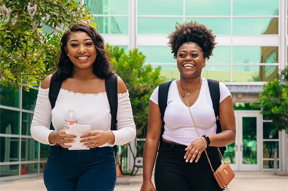 Two students smiling and walking