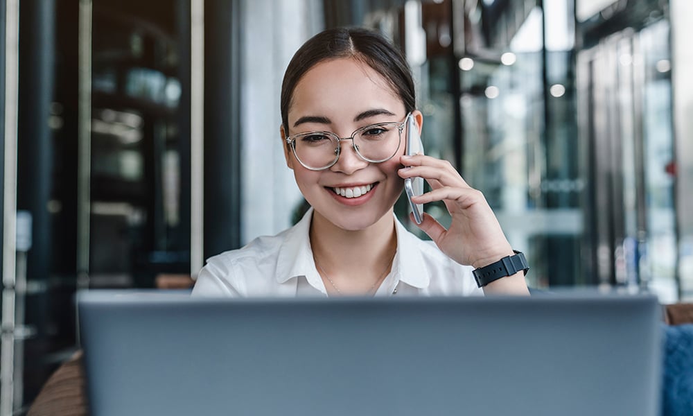 Female student looking at her laptop screen while smiling