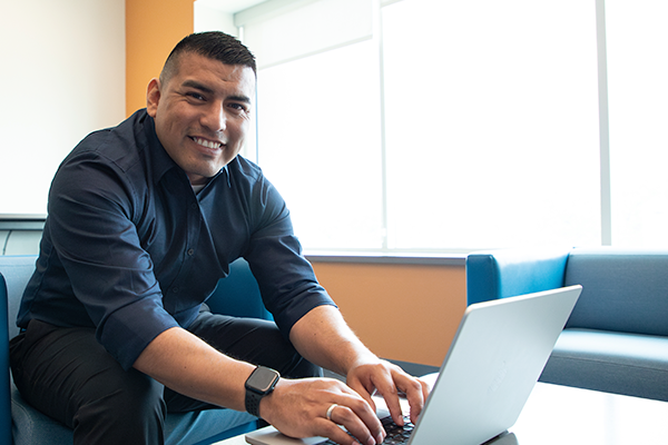 Candido a male AlamoONLINE student on his laptop.