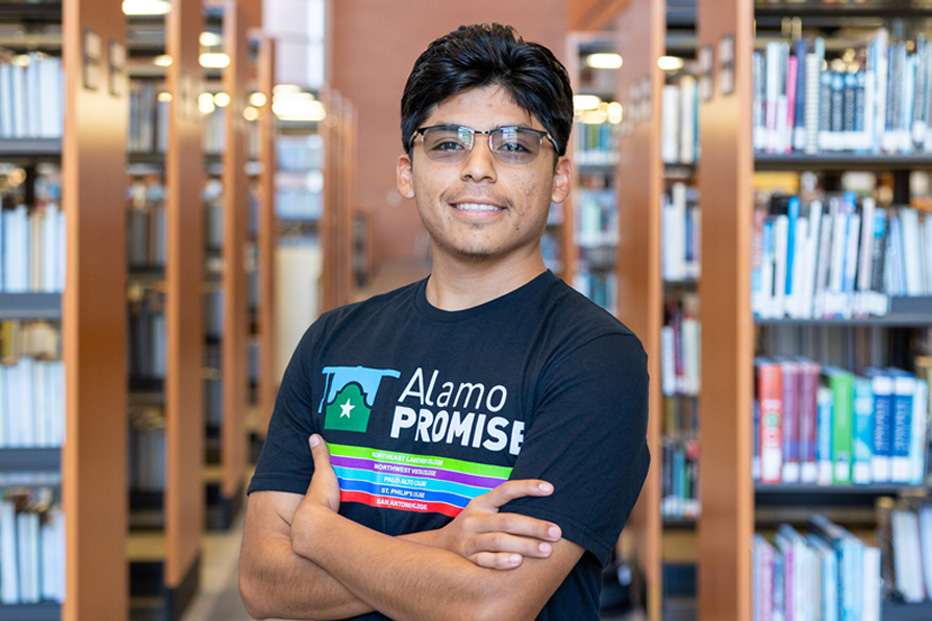 male student standing in between bookcases in library