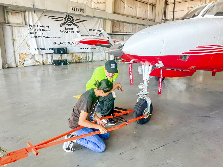 a student and faculty member working on a plane front tire