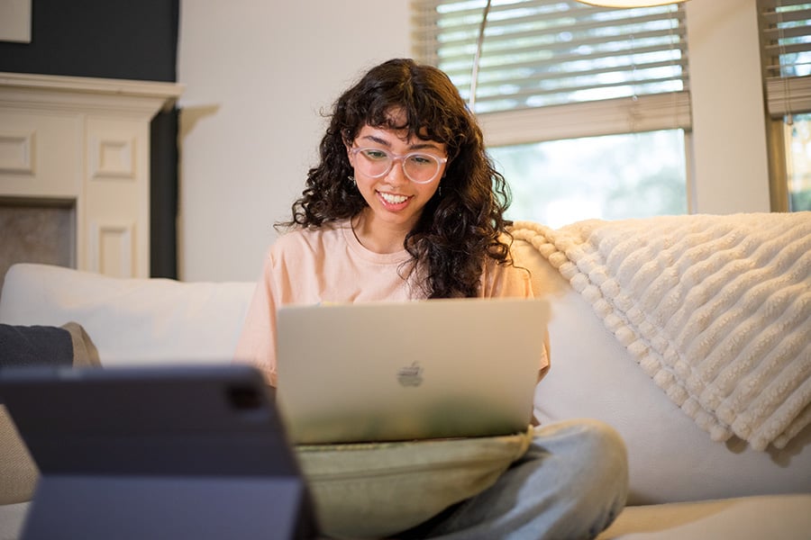 AlamoONLINE student smiling with laptop in her home