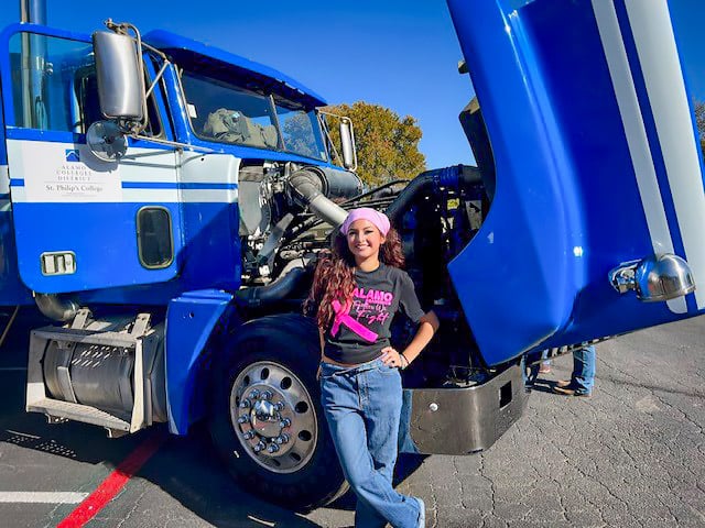 Alamo College female student in from of big truck