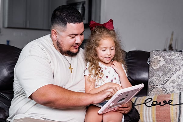 Miguel an online student at Alamo Colleges at home with his daughter.