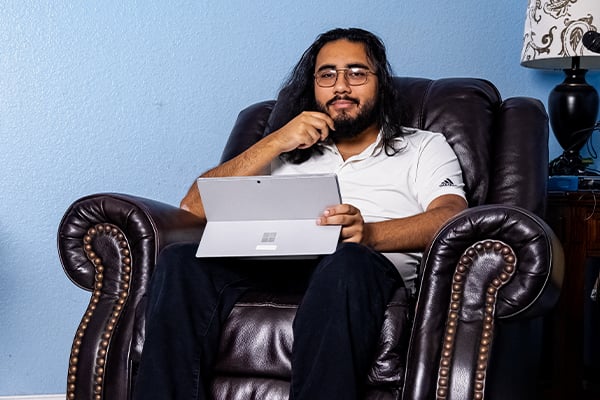 Adrian an online student at Alamo Colleges in his home on his laptop