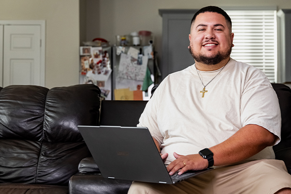 Miguel an online student at the Alamo Colleges on his laptop in his home