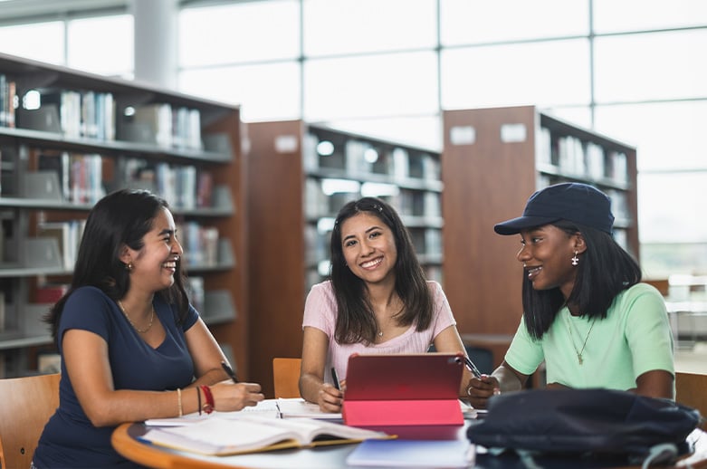 Three Women sitting in a library smiling