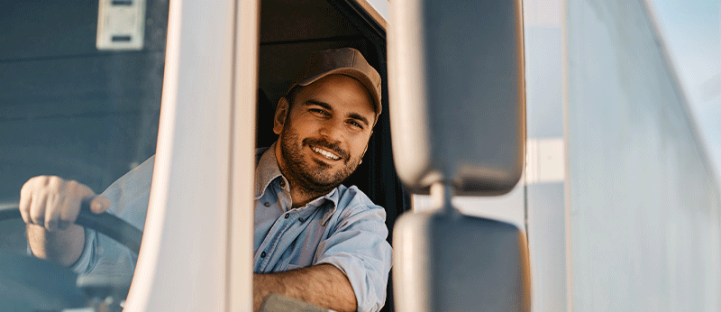 smiling man holding the wheel of a truck