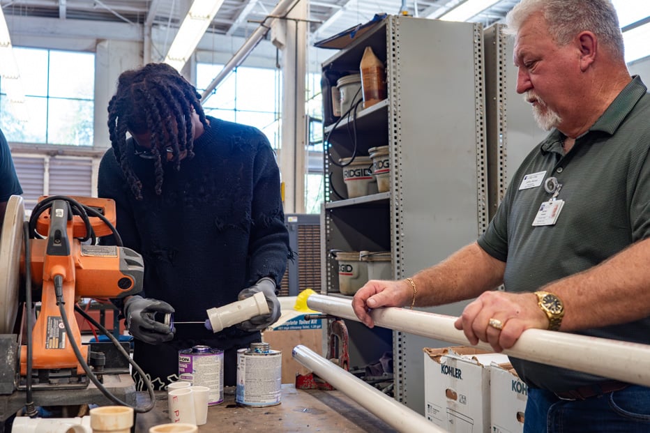 male student learning construction trade skill from male instructor