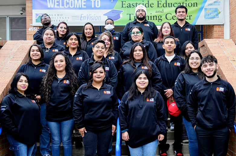 Diverse group of students in black school jackets pose on brick steps beneath an &ldquo;Eastside Education and Training Center&rdquo; welcome banner.
