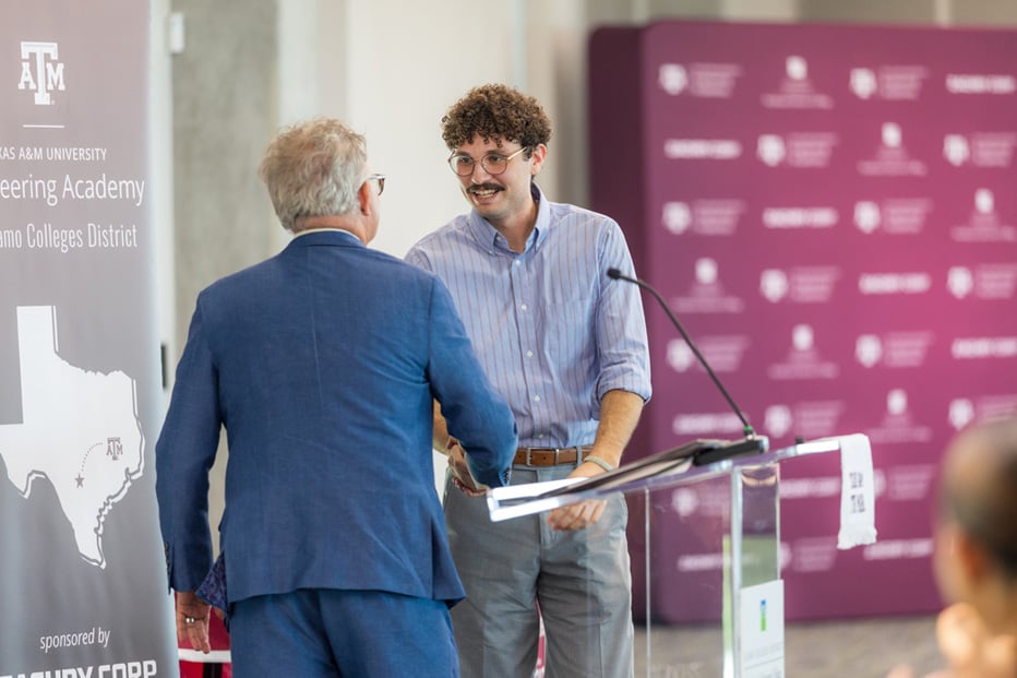 male student shaking hands with man at podium