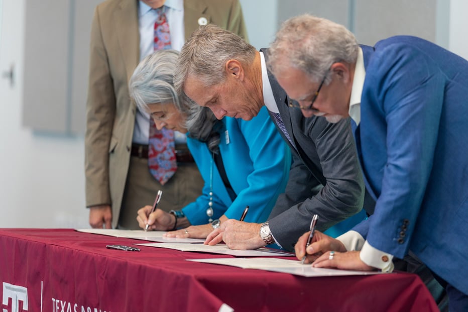 three people are signing a contract