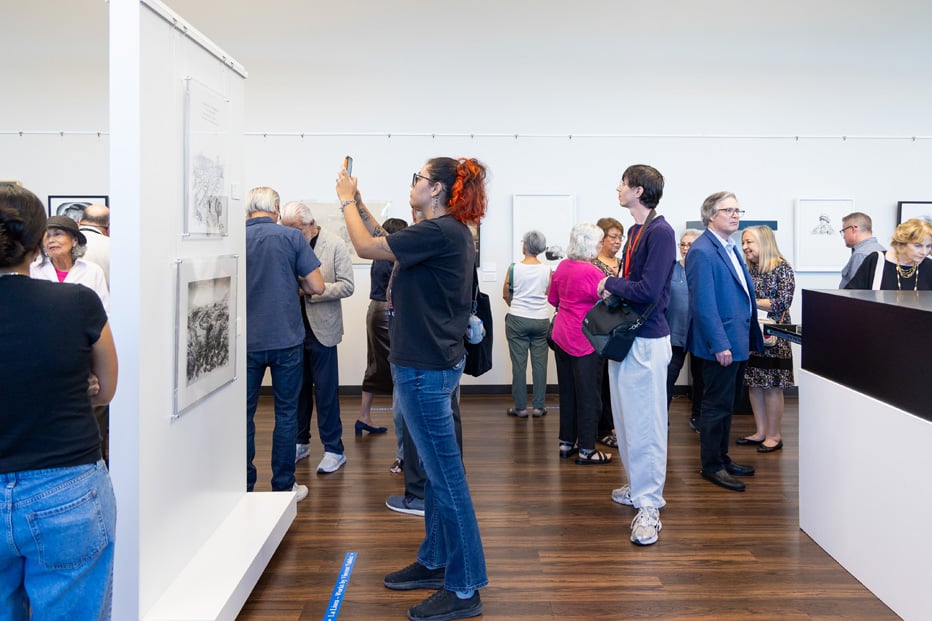 Diverse group of people taking pictures of art hung on gallery walls