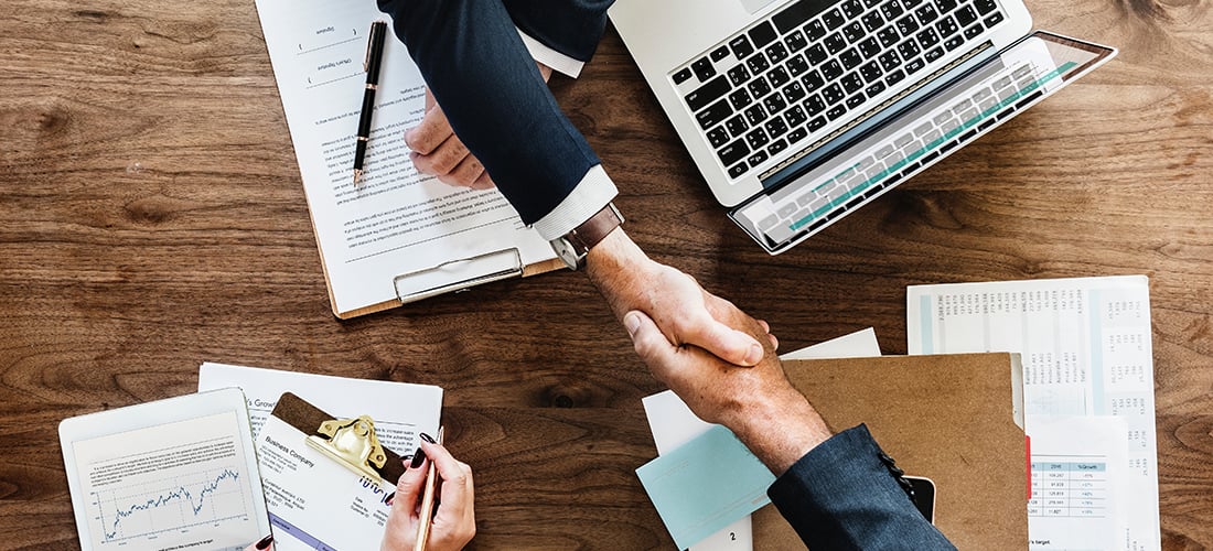 Internal Audit Two people shaking hands over documents