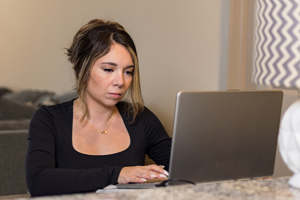 Aida an AlamoONLINE ambassador on her laptop in her home