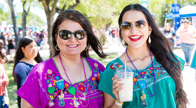 Two women wearing fiesta medals and smiling